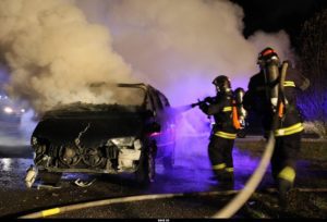 Des sapeurs-pompiers éteignent une voiture brûlée.